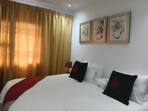 a bedroom with a large white bed with two pillows at Russell's Rest Apartments in Johannesburg