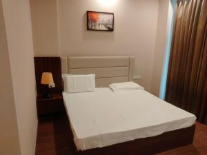 a small bedroom with a bed with white sheets at Velvet Nook in Greater Noida +10 photos