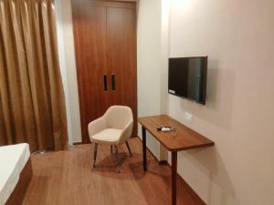a room with a desk and a chair and a television at Velvet Nook in Greater Noida