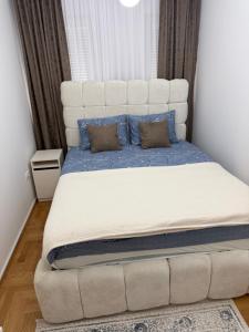 a bedroom with a large white bed with blue pillows at Stan na dan Alex in Bijeljina