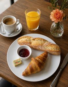 a plate with two croissants and a cup of coffee and orange juice at L'Aiguille Creuse in Étretat
