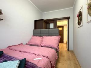 a bed with a pink comforter in a room at Apartament Solankowa Róża in Inowrocław