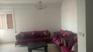 a living room with two red couches and a chandelier at Gharbi in Bizerte