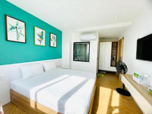 a bedroom with a white bed and a green wall at The Track Homestay - Near Bai Dai Beach in Cam Lâm