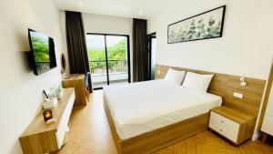 a bedroom with a bed and a tv and a balcony at The Track Homestay - Near Bai Dai Beach in Cam Lâm
