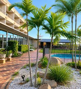 a resort with palm trees and a swimming pool at Lumina Motel Gladstone in Gladstone