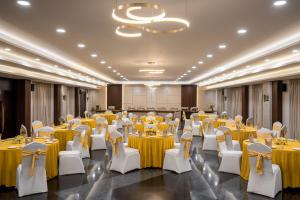 a banquet hall with yellow tables and white chairs at TSG Emerald View Hotel and SPA in Port Blair