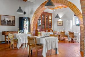 a restaurant with white tables and chairs and a brick archway at Tenuta La Fratta in Sinalunga