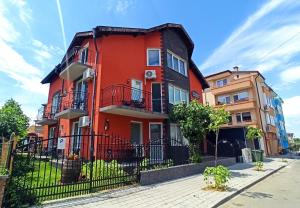 an orange building with a fence in front of it at Guest House Sunflowers in Pomorie