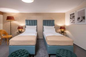 two beds in a room with two chairs and lamps at Zámecký hotel & Wellness in Poděbrady