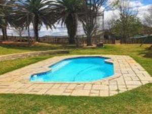 a large blue swimming pool in a yard at Emahlathini Guest Farm in Piet Retief