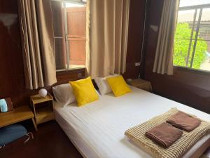 a bedroom with a bed with yellow pillows and a window at taitoon hostel&cafe in Chiang Rai
