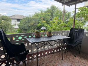 a table and chairs on a balcony with a view at taitoon hostel&cafe in Chiang Rai