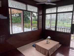 a room with a table and windows in a room at taitoon hostel&cafe in Chiang Rai