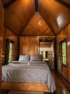 a bed in a room with wooden walls and windows at Tetebatu Garden Lombok in Tetebatu