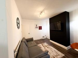 a living room with a couch and a flat screen tv at Spacious 3 Bed , Free Parking , Fast WiFi , Long Stays in Kettering