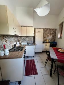 a small kitchen with white cabinets and a table with a red at Estía Holidays Apartments - Taormina in Taormina