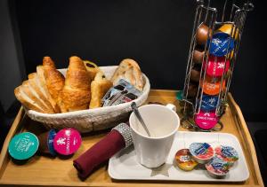 a tray with a basket of bread and a cup of coffee at Appartement tout confort avec balnéo et lit king size in Pézenas
