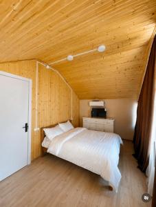 a bed in a room with a wooden ceiling at Mountain Shadow Racha in Ambrolauri