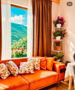 an orange couch in a living room with a window at Mountain Shadow Racha in Ambrolauri