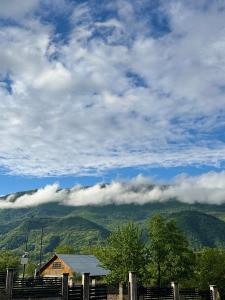 a house on top of a mountain with clouds at Mountain Shadow Racha in Ambrolauri