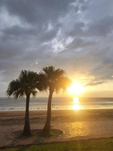 two palm trees on the beach at sunset at MATAHARI Guest house in Miyazaki
