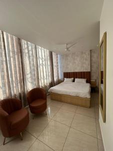 a bedroom with a bed and two chairs at Vida Hotel in Patiāla