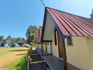 a building with a red roof and a porch at Sabda Desa Cabin in Cinyiruan