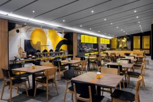 a restaurant with wooden tables and chairs and yellow walls at Kampi Hotel Sunter in Jakarta