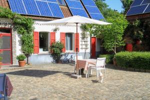 a table and chair with an umbrella in front of a house with solar panels at B&B Adem in Horebeke