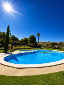 a large blue swimming pool with the sun in the sky at Bungalow with Pool & BBQ - Carabassi Beach 10' in Gran Alacant