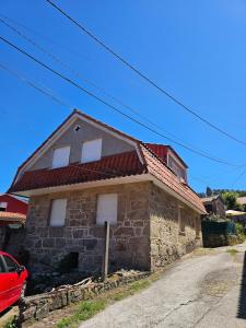 a stone house with a red roof on a street at Casa A devesa in Cangas de Morrazo +2 photos
