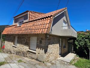an old stone house with a red roof at Casa A devesa in Cangas de Morrazo