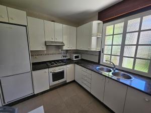 a kitchen with white cabinets and a sink at Casa A devesa in Cangas de Morrazo