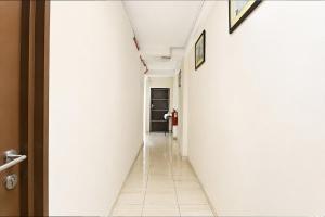 a hallway with a white wall and a door at Collection O Axlite Hotel in Taiping