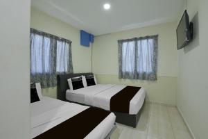 a bedroom with two beds and a flat screen tv at Collection O Axlite Hotel in Taiping