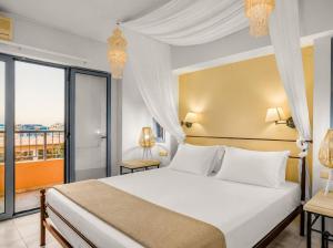 a bedroom with a large white bed and a balcony at Golden Bay Apartments-Garden Haven in Malia