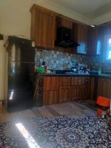 a kitchen with a black refrigerator and wooden cabinets at Urban Den Hostel in Srinagar