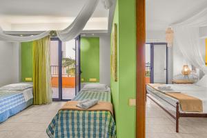 a bedroom with two beds and a green wall at Golden Bay Apartments-Garden Haven in Malia