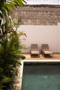 two chairs sitting on a deck next to a swimming pool at Villa Papì Uluwatu 1 in Bingin Beach