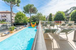 ein Schwimmbad mit Liegestühlen und ein Spielplatz in der Unterkunft Hotel Fabrizio in Rimini