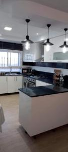 a large kitchen with white counters and a black counter top at Kelibia Jinen EL mansoura in Kelibia