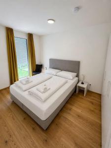 a bedroom with a bed with white sheets and a window at Am See 18 in Podersdorf am See +47 photos