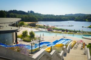 a large swimming pool next to a large body of water at Bluedothotels location France in Magnac-Laval
