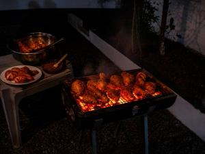 a grill with chicken on it with a plate of food at BIKI'S PALM VILLA in Kaduturutti