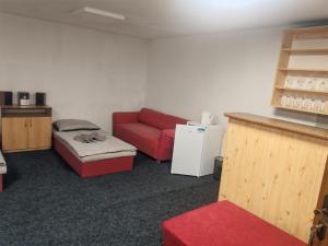 a living room with a red couch and a refrigerator at Penzion Nord in Hora Svatého Šebestiána