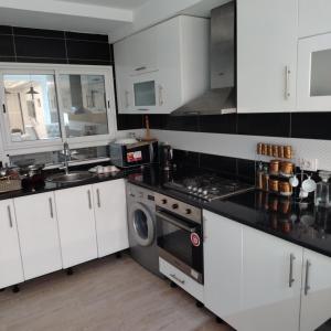 a kitchen with white cabinets and a stove top oven at Kelibia Jinen EL mansoura in Kelibia