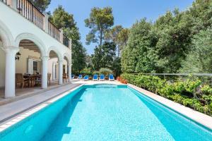an outdoor swimming pool with blue chairs next to a house at Casa Gotmar 132 in El Port