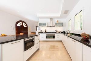 a kitchen with white cabinets and black counter tops at Casa Gotmar 132 in El Port