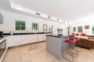 a kitchen with white cabinets and red bar stools at Casa Gotmar 132 in El Port +21 photos